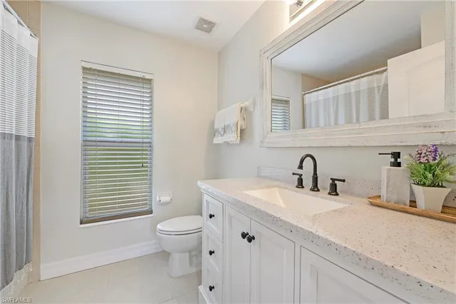 a bathroom with a granite countertop sink toilet and mirror