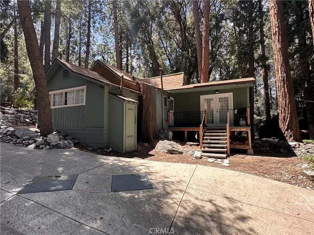a view of house with backyard and trees in the background