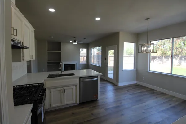 a kitchen with stainless steel appliances granite countertop a sink a stove and a wooden floors