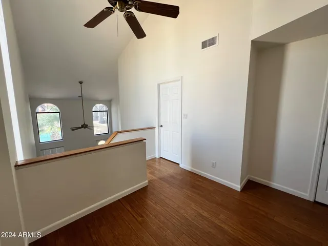 an empty room with wooden floor fan and windows