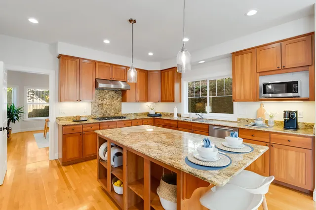 a kitchen with stainless steel appliances granite countertop a kitchen island a stove a sink a dining table and chairs