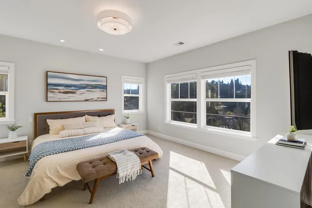 a bedroom with a bed and a flat tv screen on dresser