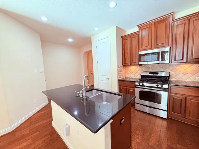 a kitchen with stainless steel appliances granite countertop a sink a stove and a refrigerator