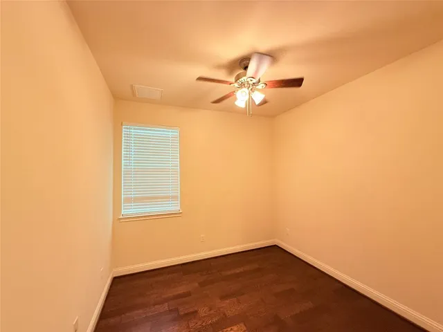 an empty room with a window and chandelier fan