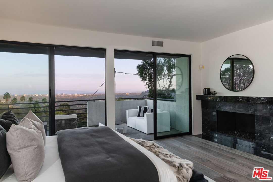 1500 Inverness Drive Pasadena, CA 91103 - Photo 35 of 66 a bedroom with a bed a fireplace and a large window with balcony view