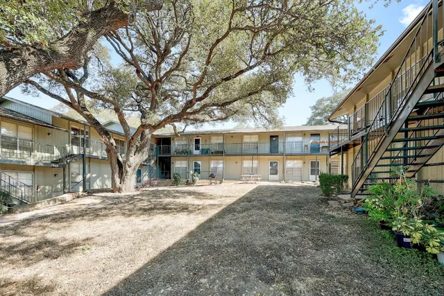 a view of backyard with large trees and wooden fence
