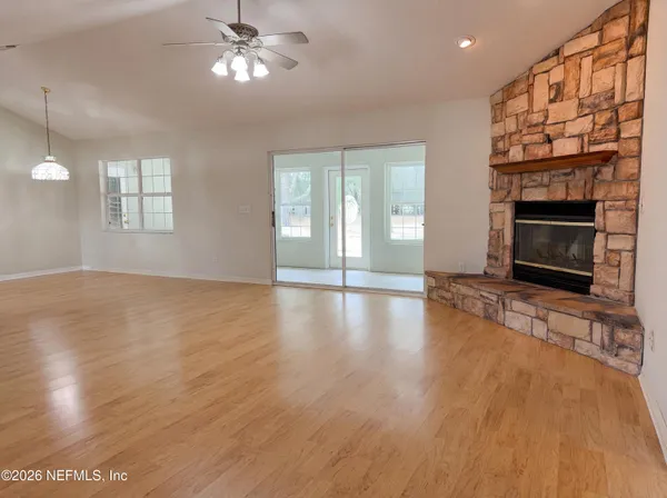 an empty room with wooden floor fireplace and windows