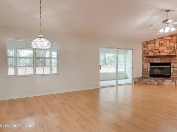 a view of an empty room with window and wooden floor