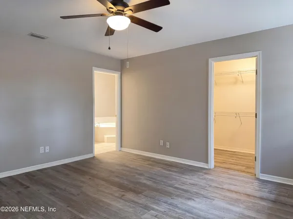 an empty room with wooden floor closet and windows