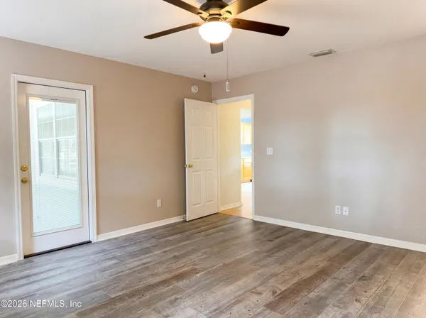 an empty room with wooden floor fan and windows