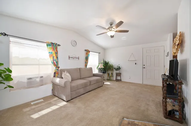 a living room with furniture a ceiling fan and a window