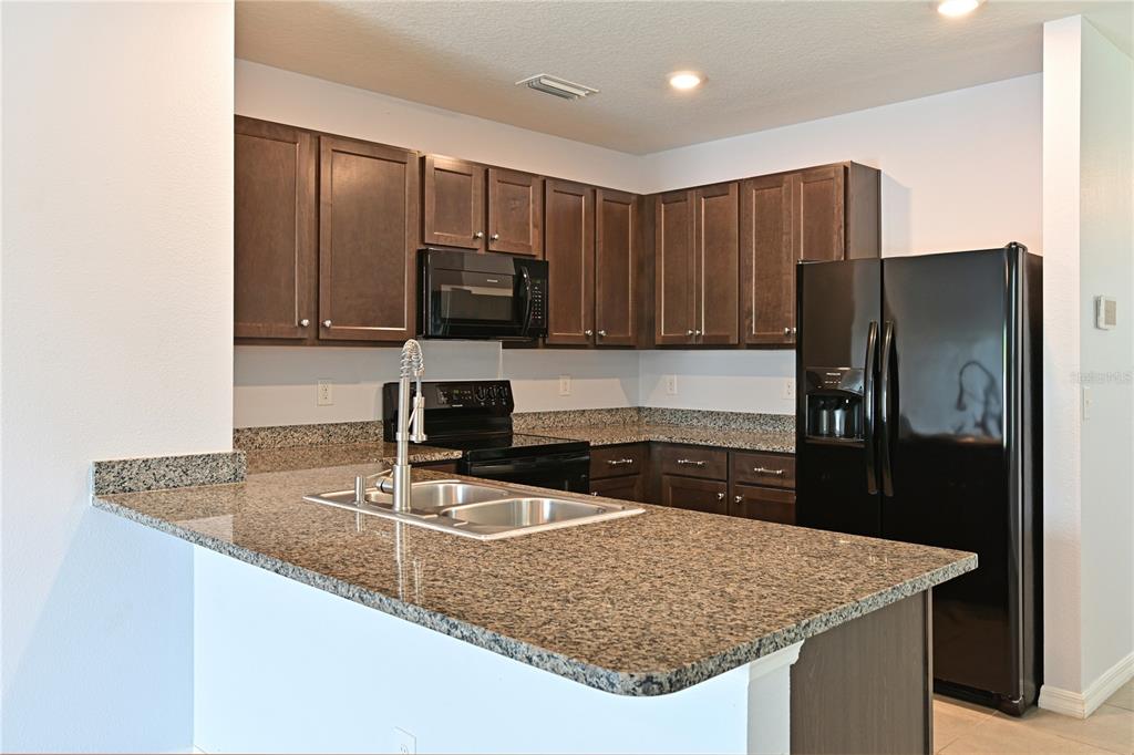 4919 Wedgeleaf Way Palmetto, FL 34221 - Photo 19 of 35 a kitchen with stainless steel appliances granite countertop a sink refrigerator and microwave