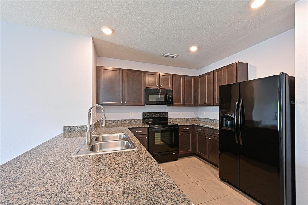 4919 Wedgeleaf Way Palmetto, FL 34221 - Photo 22 of 35 a kitchen with stainless steel appliances granite countertop a refrigerator sink and stove