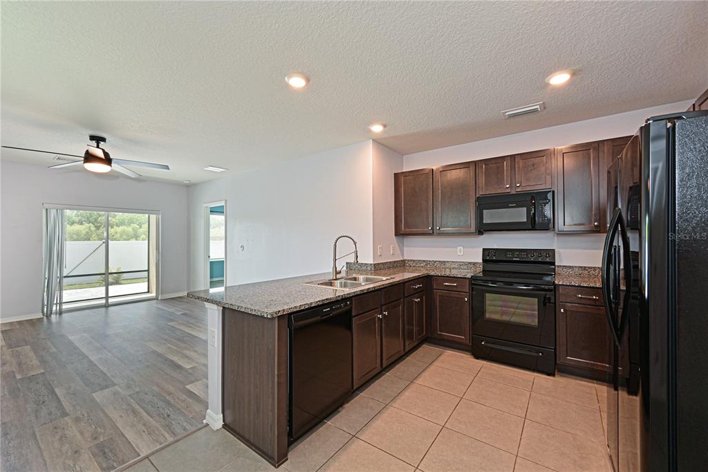 4919 Wedgeleaf Way Palmetto, FL 34221 - Photo 9 of 35 a kitchen with stainless steel appliances granite countertop a stove a refrigerator and a sink