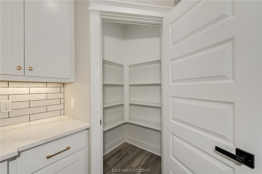 2908 GOLDBERG Drive Bryan, TX 77808 - Photo 19 of 44 Modern kitchen features: stainless steel appliances, quartz countertops, island, decorative pendant lights, vinyl flooring, and tile backsplash.