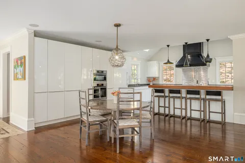 a kitchen with stainless steel appliances kitchen island granite countertop a table chairs and a wooden floor
