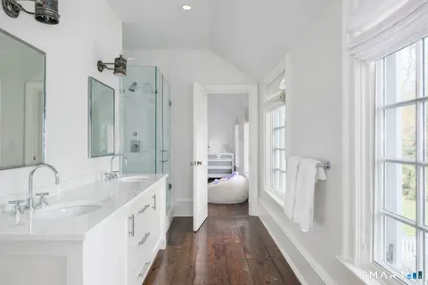 a spacious bathroom with a double vanity sink a mirror and a shower