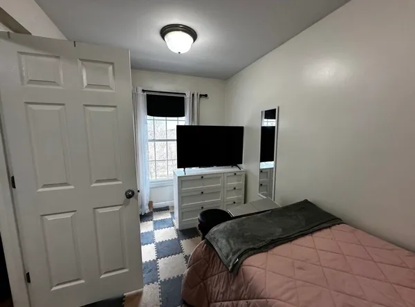 a bedroom with a bed tv and a window
