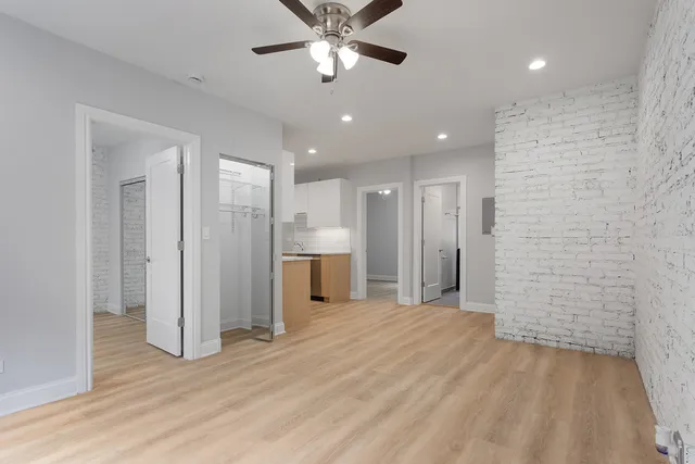 a view of a livingroom with a chandelier fan and refrigerator in a kitchen