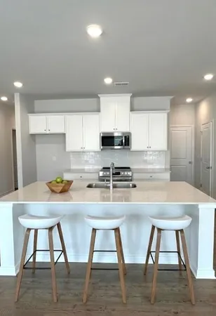 a kitchen with stainless steel appliances granite countertop a stove top oven a sink counter space and chairs