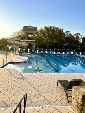 a view of a lake with a bench and lawn chairs