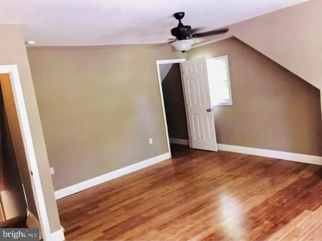 a view of a hallway with wooden floor and a ceiling fan