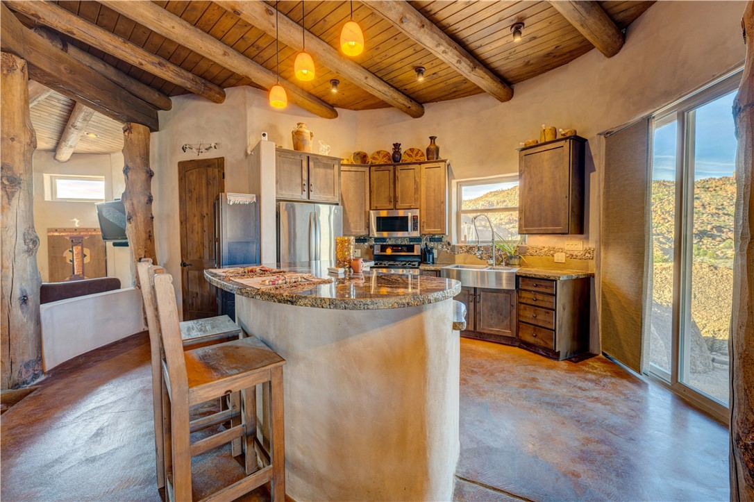 17445 South La Cienega Ranch Road Yucca, AZ 86438 - Photo 11 of 52 a dining room with stainless steel appliances kitchen island granite countertop a refrigerator a stove and a dining table with wooden floor