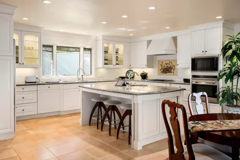 a kitchen with stainless steel appliances granite countertop a table chairs sink and cabinets