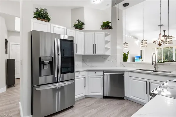 a kitchen with stainless steel appliances white cabinets and wooden floors