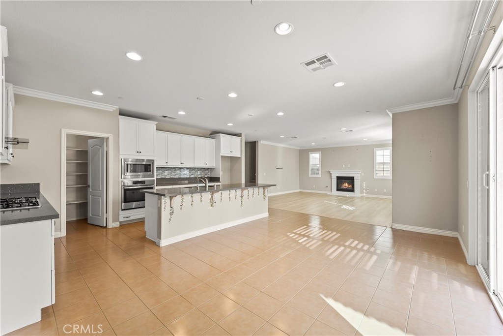 9719 La Vine Court Rancho Cucamonga, CA 91701 - Photo 8 of 39 a large white kitchen with kitchen island a sink a stove a refrigerator and a living room view