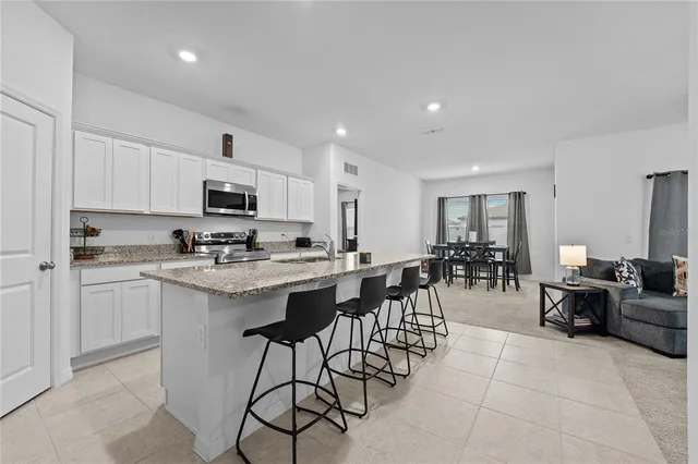 a kitchen with stainless steel appliances granite countertop a table and chairs in it