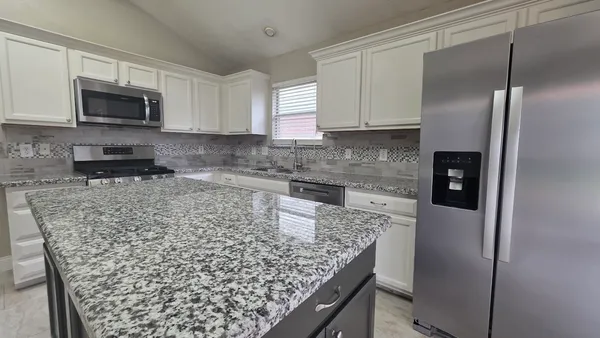 a kitchen with stainless steel appliances granite countertop a refrigerator sink and microwave
