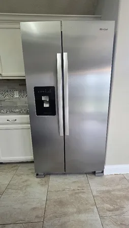 a view of a refrigerator in kitchen and an empty room
