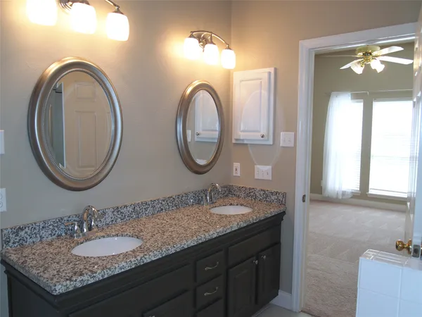 a bathroom with a granite countertop double vanity sink and a mirror