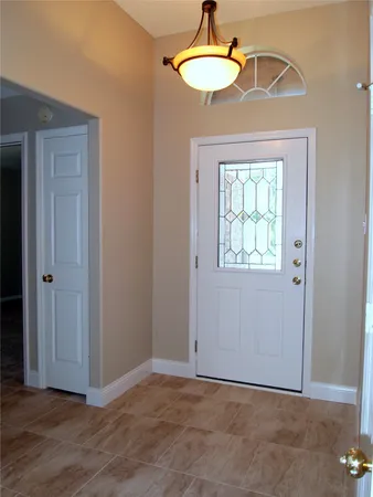 an empty room with wooden floor a chandelier fan and windows