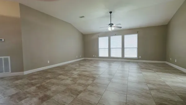 an empty room with windows and chandelier fan