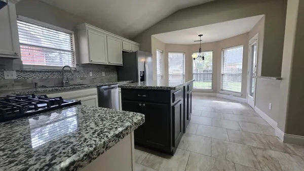 a kitchen with granite countertop a stove a sink dishwasher and a refrigerator
