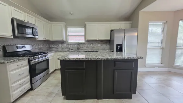 a kitchen with granite countertop a sink dishwasher a stove and a refrigerator