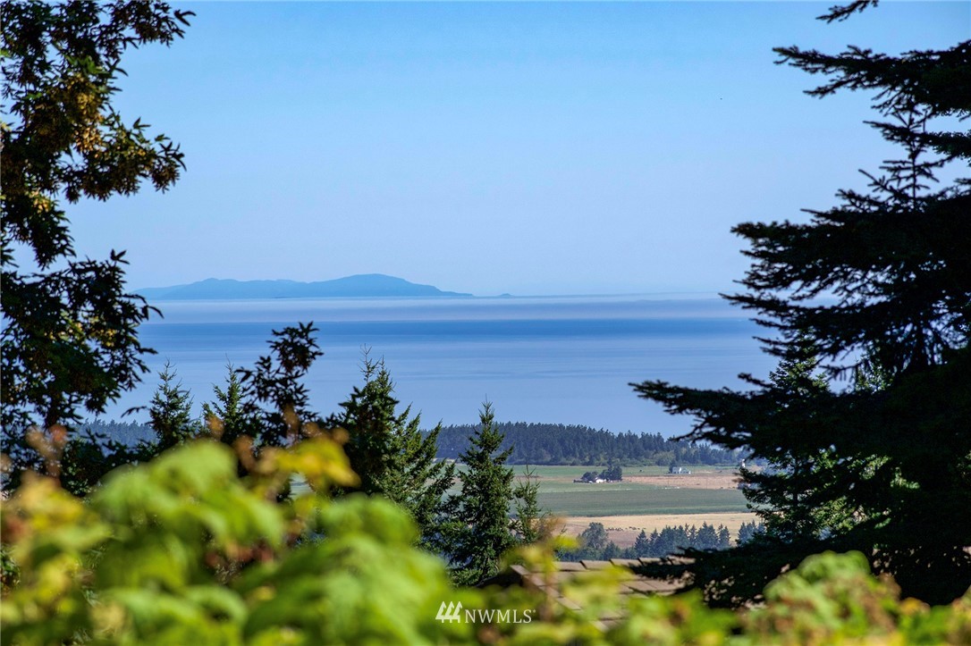 9999 Ravens Ridge Road Sequim, WA 98382 - Photo 22 of 40 a view of a lake with a building in the background