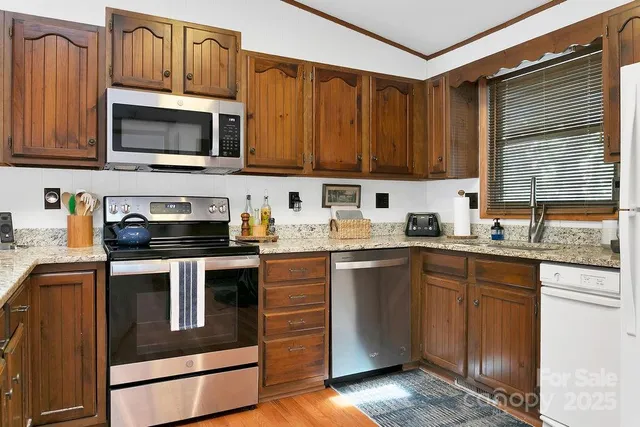 a kitchen with stainless steel appliances granite countertop a stove a sink dishwasher and a microwave oven on the blue kitchen countertops