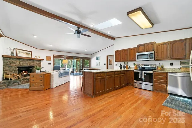 a kitchen with stainless steel appliances kitchen island granite countertop a stove top oven a sink dishwasher a dining table and chairs with wooden floor