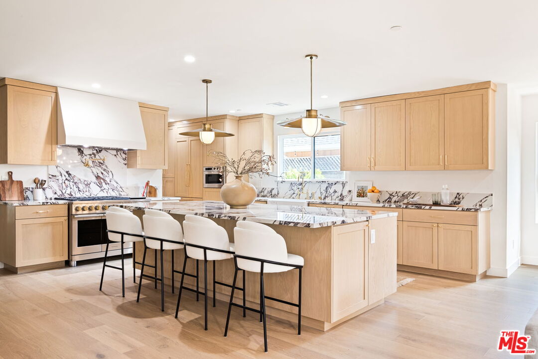 a kitchen with stainless steel appliances kitchen island granite countertop a stove a sink and white cabinets with wooden floor