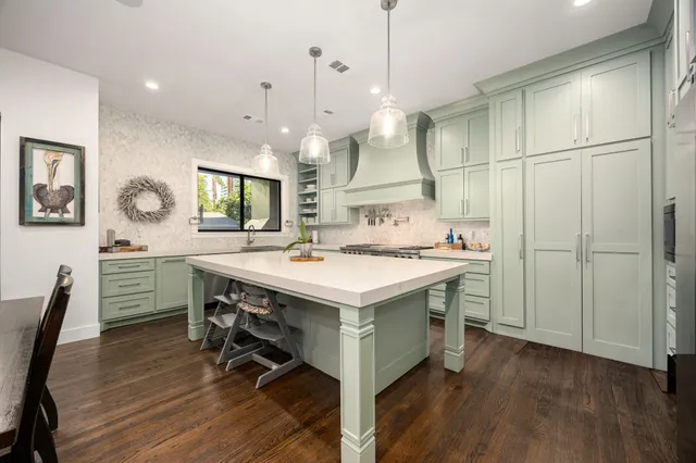 a kitchen with kitchen island a stove a sink a dining table and chairs with wooden floor