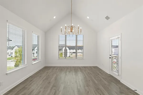 an empty room with wooden floor and stainless steel appliances