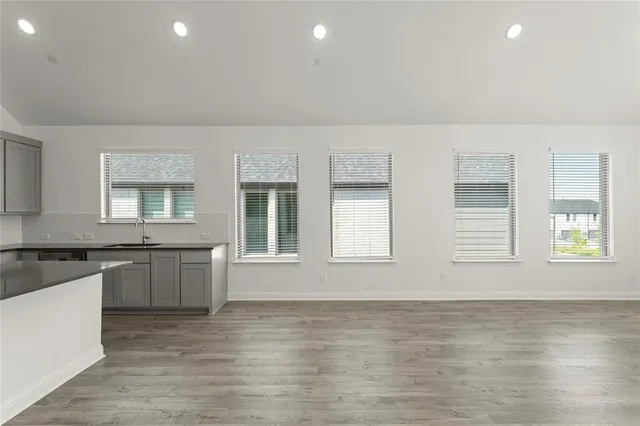 an empty room with wooden floor and stainless steel appliances