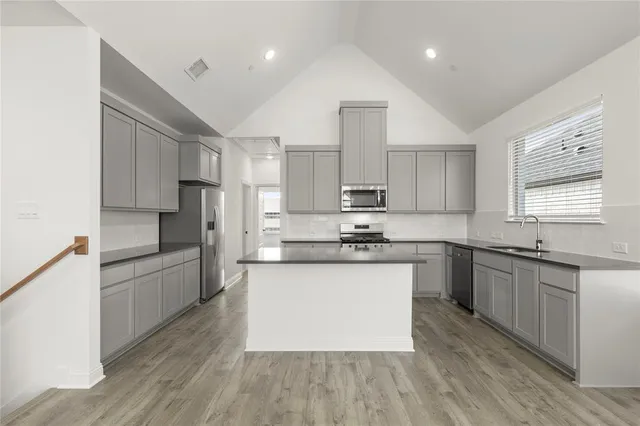 a large kitchen with stainless steel appliances kitchen island granite countertop a stove a sink dishwasher and a refrigerator