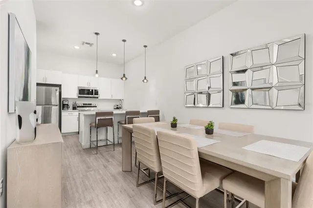 a kitchen with stainless steel appliances a refrigerator a sink a stove a dining table and chairs