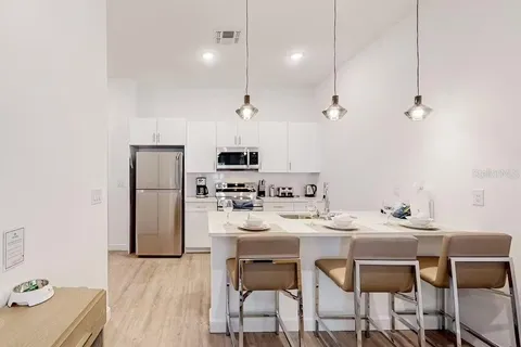 a kitchen with stainless steel appliances kitchen island granite countertop a dining table chairs and a refrigerator