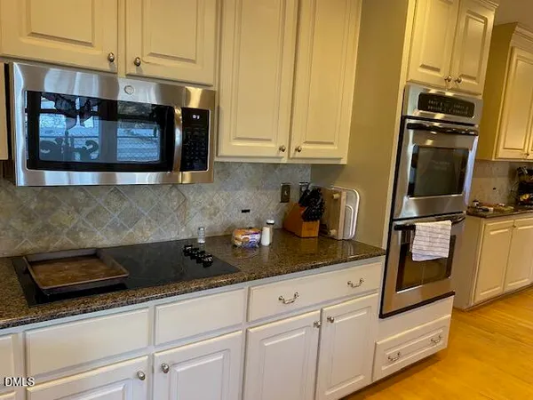 a kitchen with stainless steel appliances granite countertop white cabinets and stove
