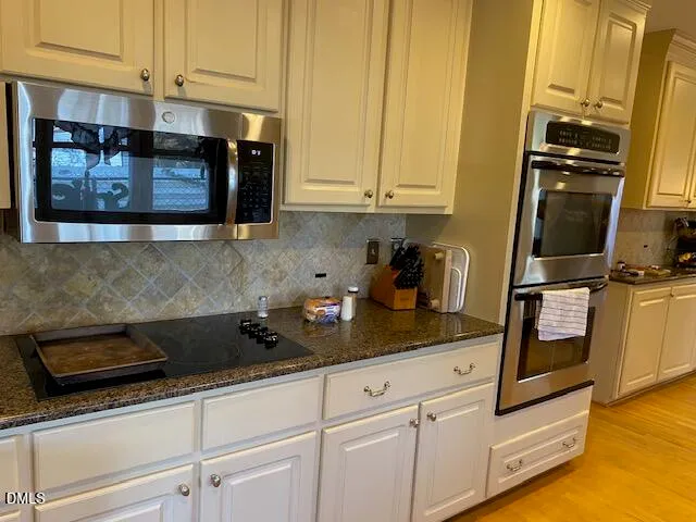 a kitchen with stainless steel appliances granite countertop white cabinets and stove